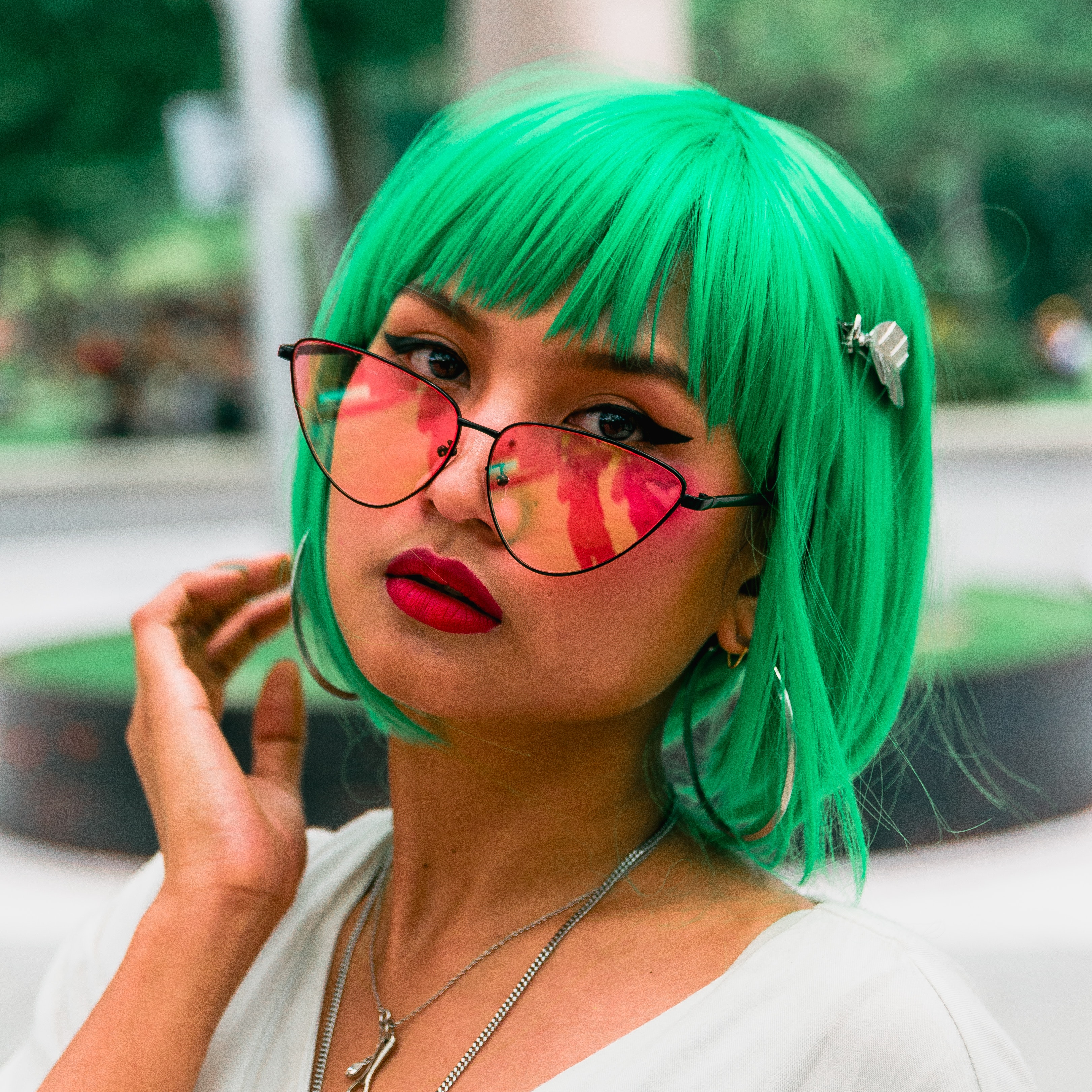 woman with greeen hair and red tint sunglasses