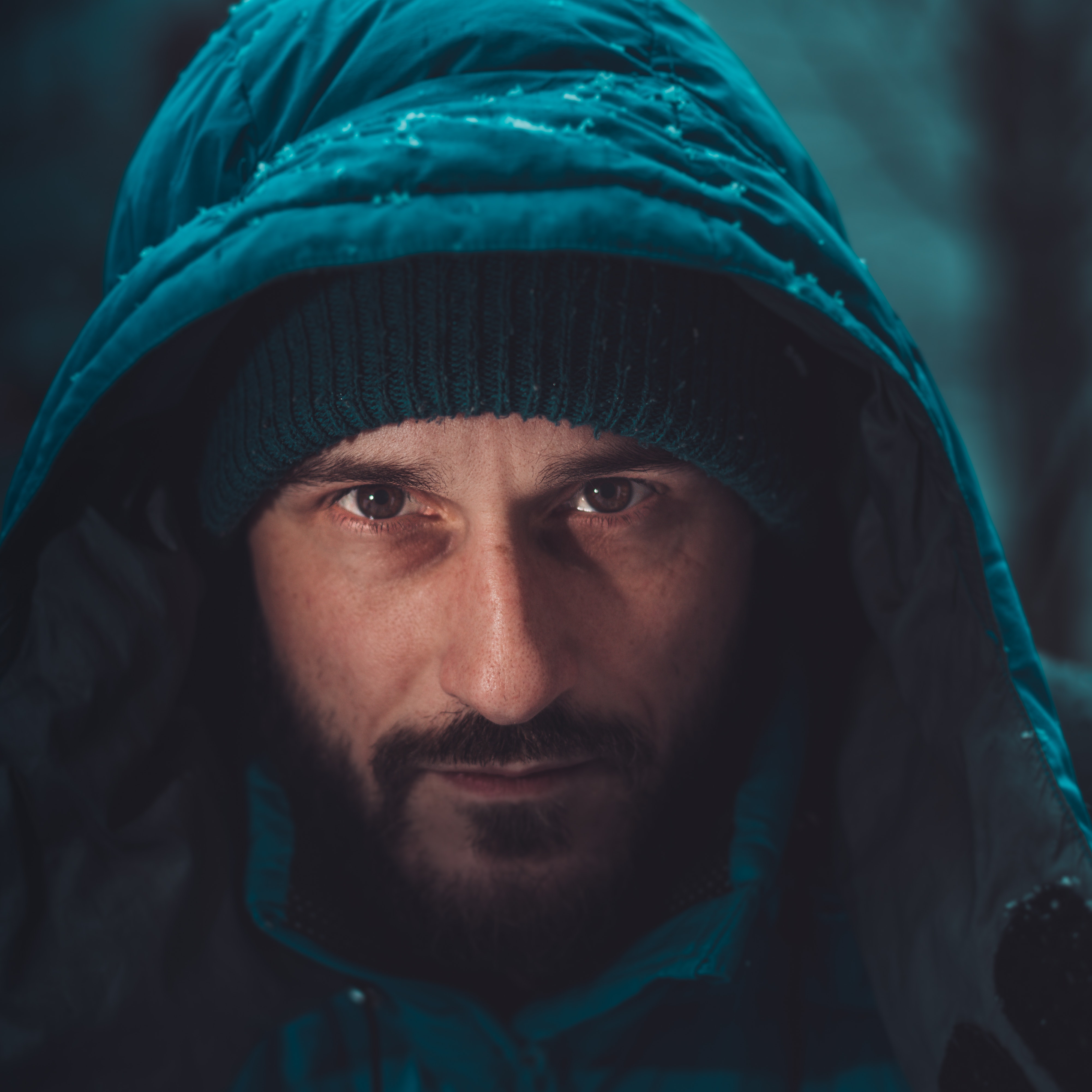 man in teal snow jacked with hood up