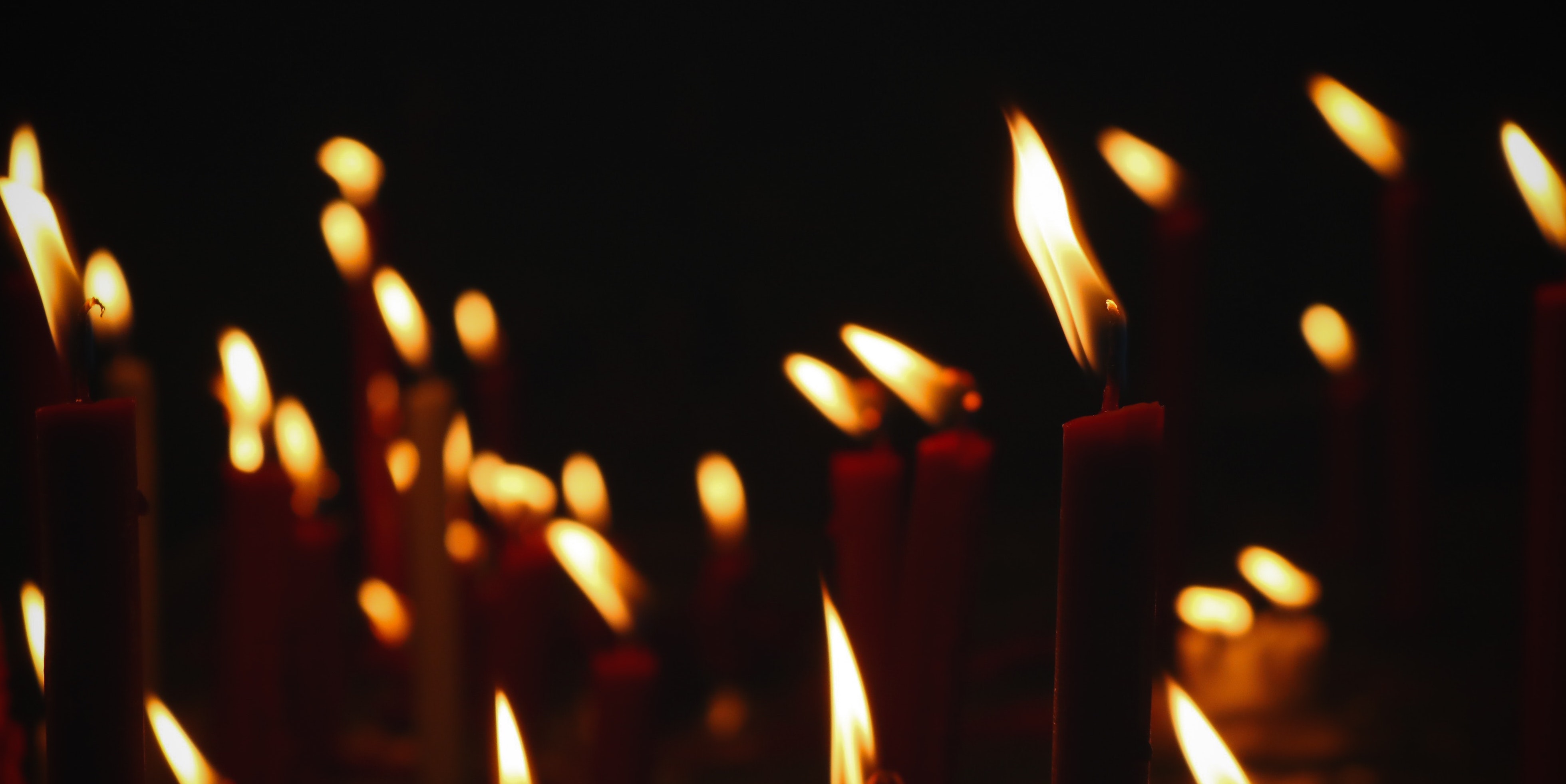 dozens of lit candles in the dark