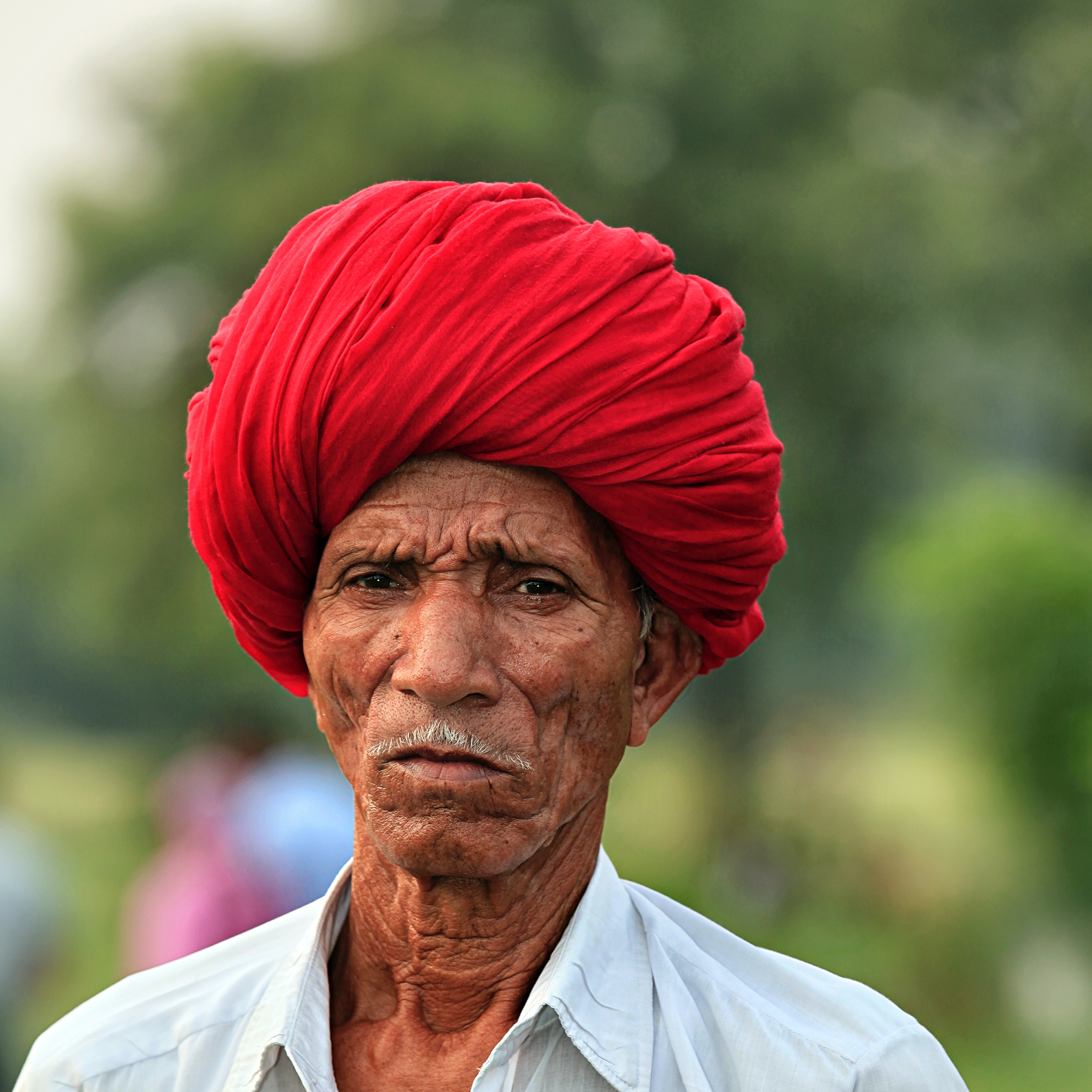older man with white mustache and red turban
